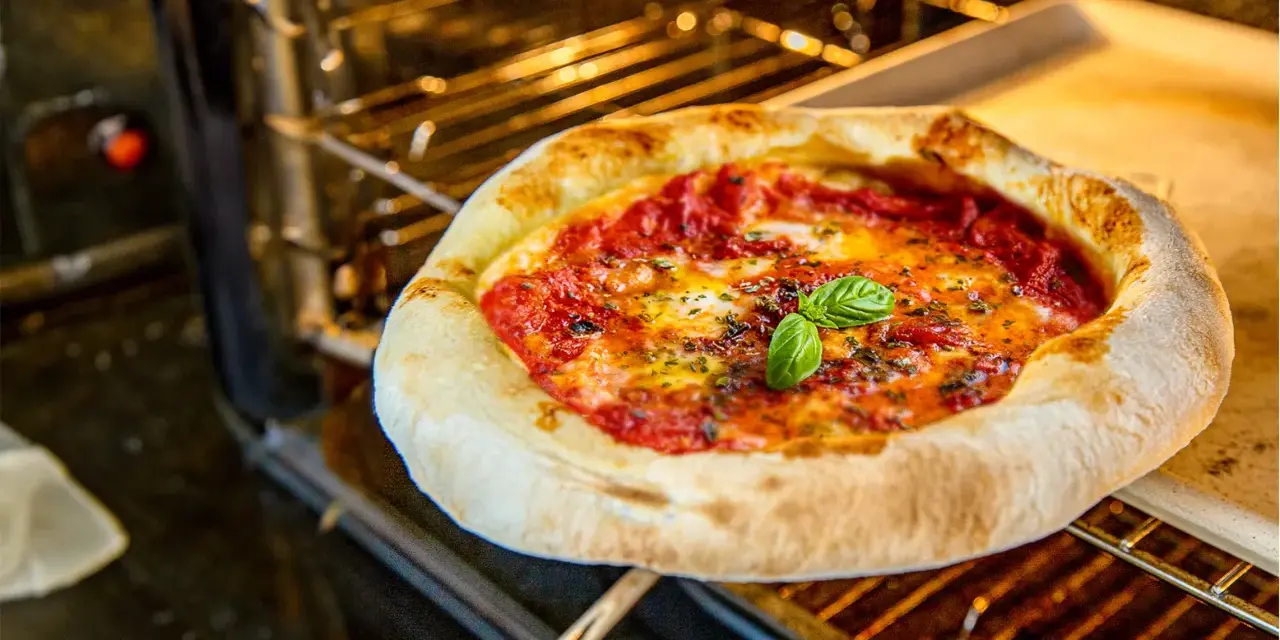 Frisch gebackene Pizza Margherita ohne Backpapier auf einem Ofenrost, mit geschmolzenem Käse und frischem Basilikum.