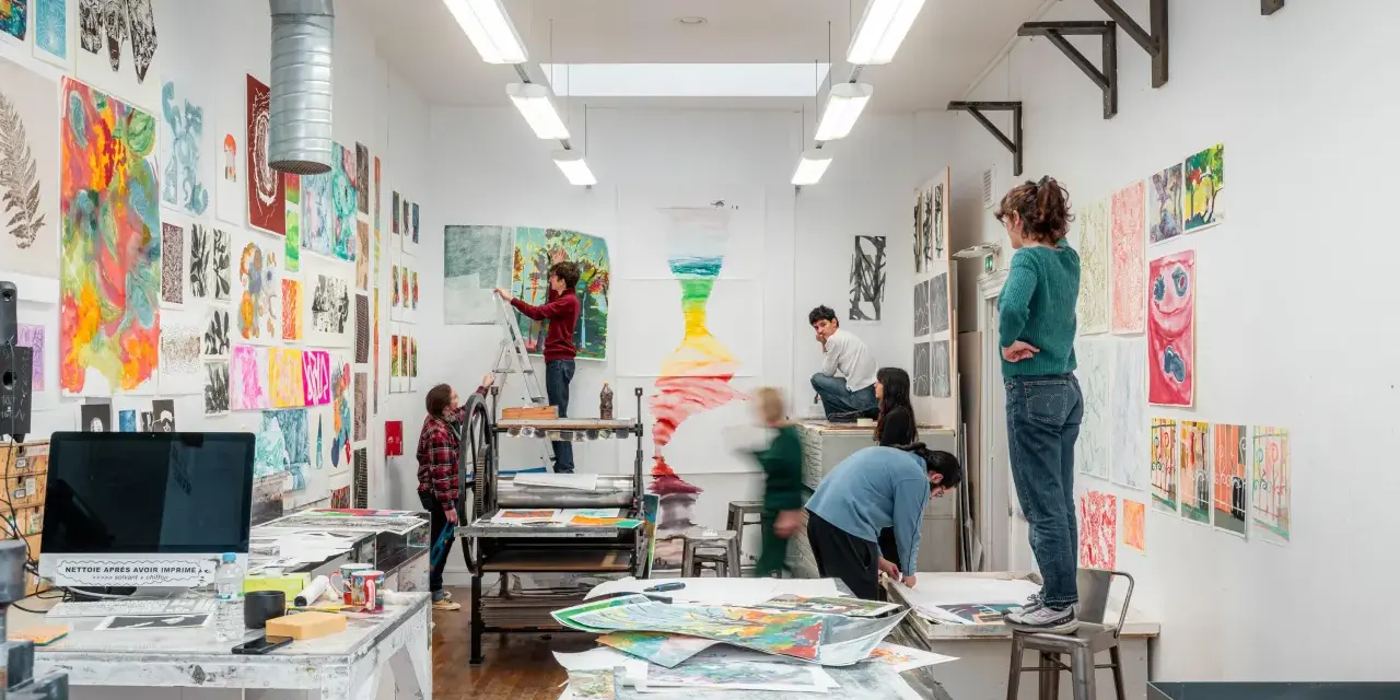 Dans une école d'art animée, des étudiants travaillent sur leurs créations, entourés d'œuvres colorées.