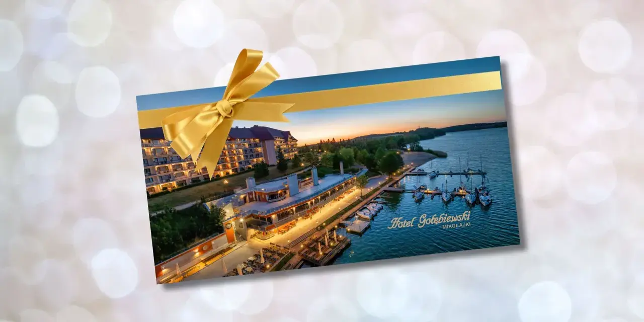 Złota karta Gołębiewski jak otrzymać? Voucher na pobyt w Hotelu Gołębiewski Mikołajki, ozdobiony złotą wstążką.