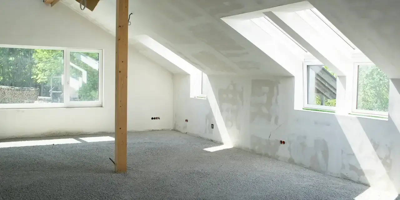 Sottotetto in costruzione con pareti in cartongesso e un pavimento in materiale granulare, pronto per essere calpestabile.