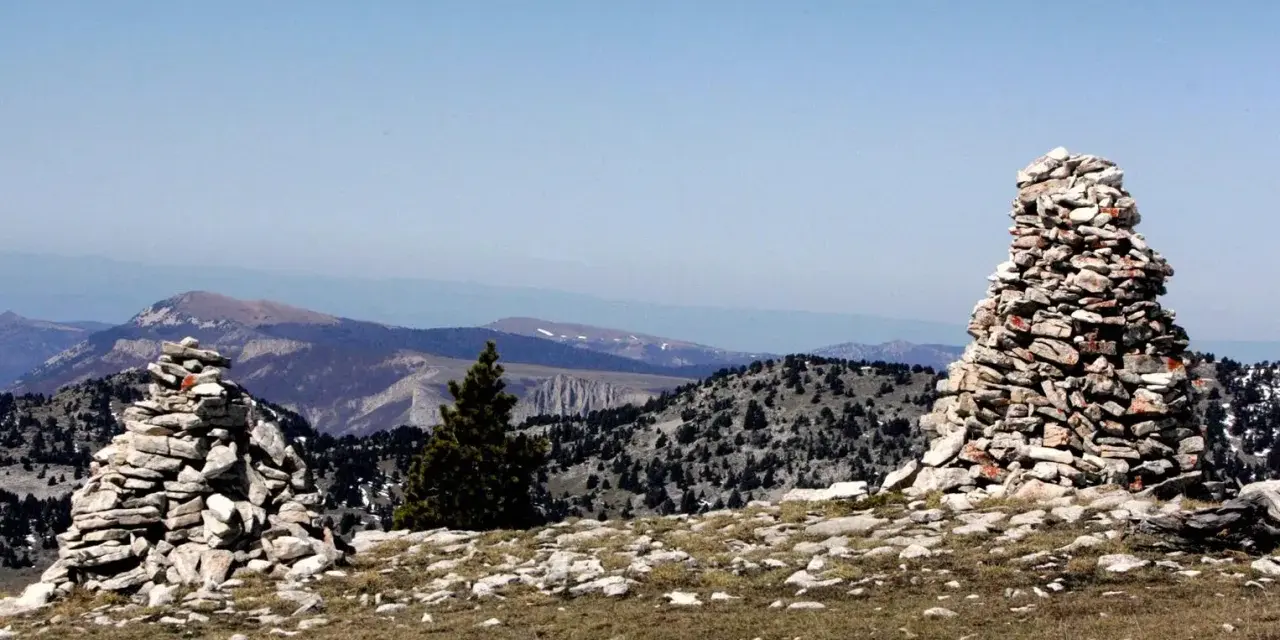 Deux cairns de cailloux marquent le paysage montagneux, offrant des repères visuels sur le sentier.