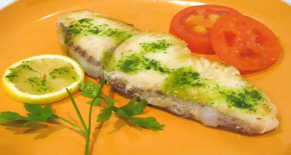 Marrajo a la plancha con perejil y limón, acompañado de rodajas de tomate fresco.
