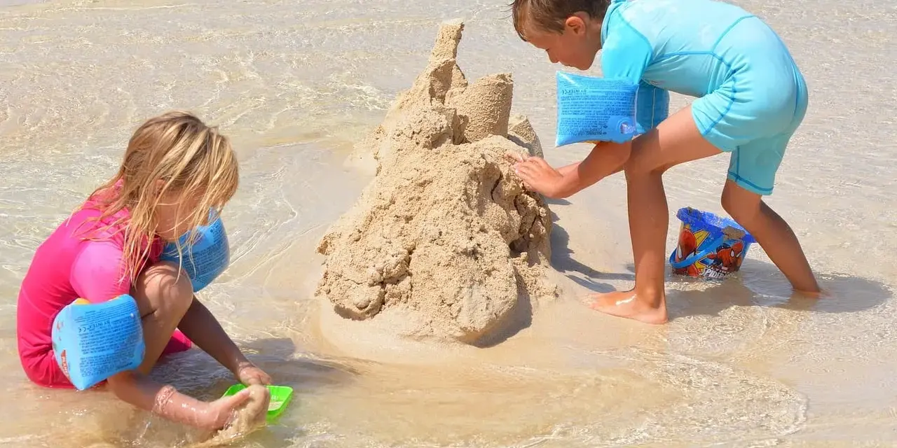 Enfants construisant un château de sable, une scène typique d'accueil centre de loisirs en bord de mer.