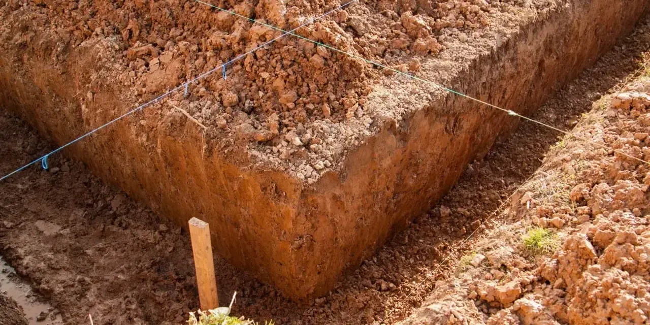 Wykonano wykopy pod fundamenty. Widać głębokie rowy w ziemi, wyznaczone sznurkami.