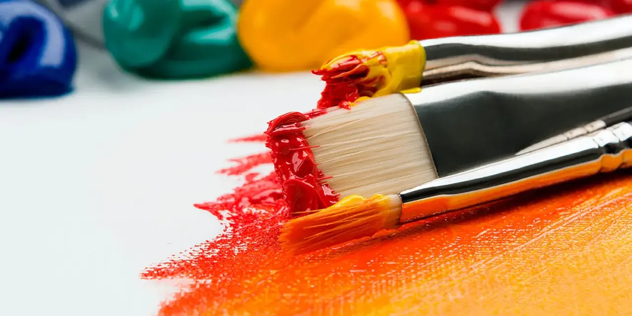 Des pinceaux chargés de peinture rouge et jaune créent une traînée vibrante sur une toile blanche. La question est : peut-on peindre directement sur une toile ? Oui !