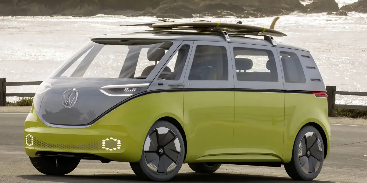 Volkswagen ID. Buzz w kolorze limonkowym z deskami surfingowymi na dachu, nad morzem.