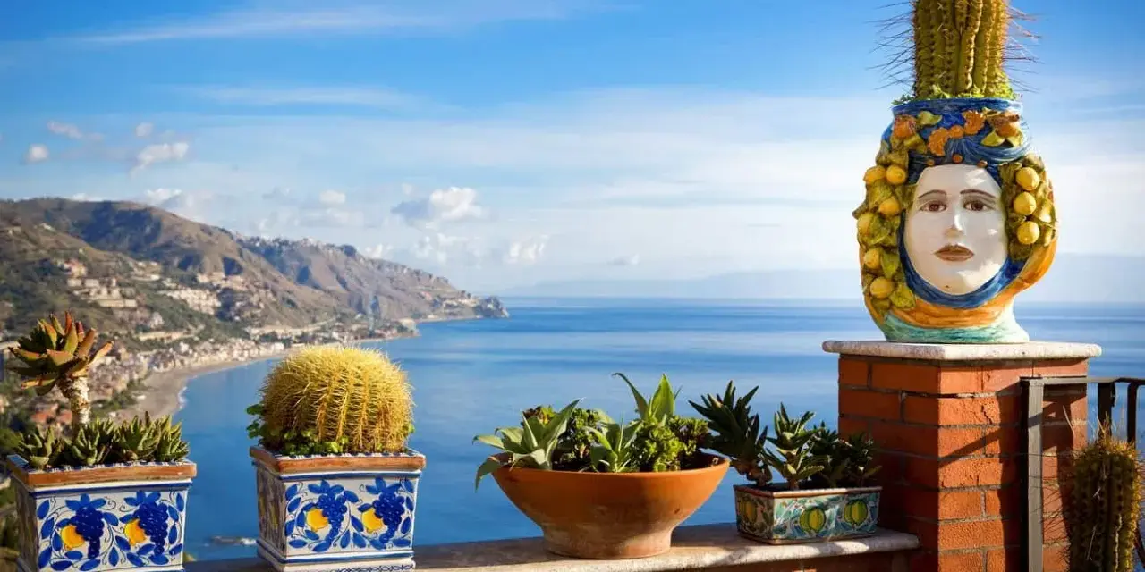 Balcone fiorito con vista sul mare, uno dei luoghi più belli della Sicilia. Cactus e piante grasse adornano la terrazza con vista sulla costa.