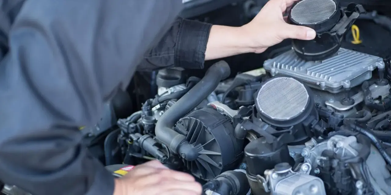 Meccanico che controlla il debimetro auto, un componente essenziale per il corretto funzionamento del motore.