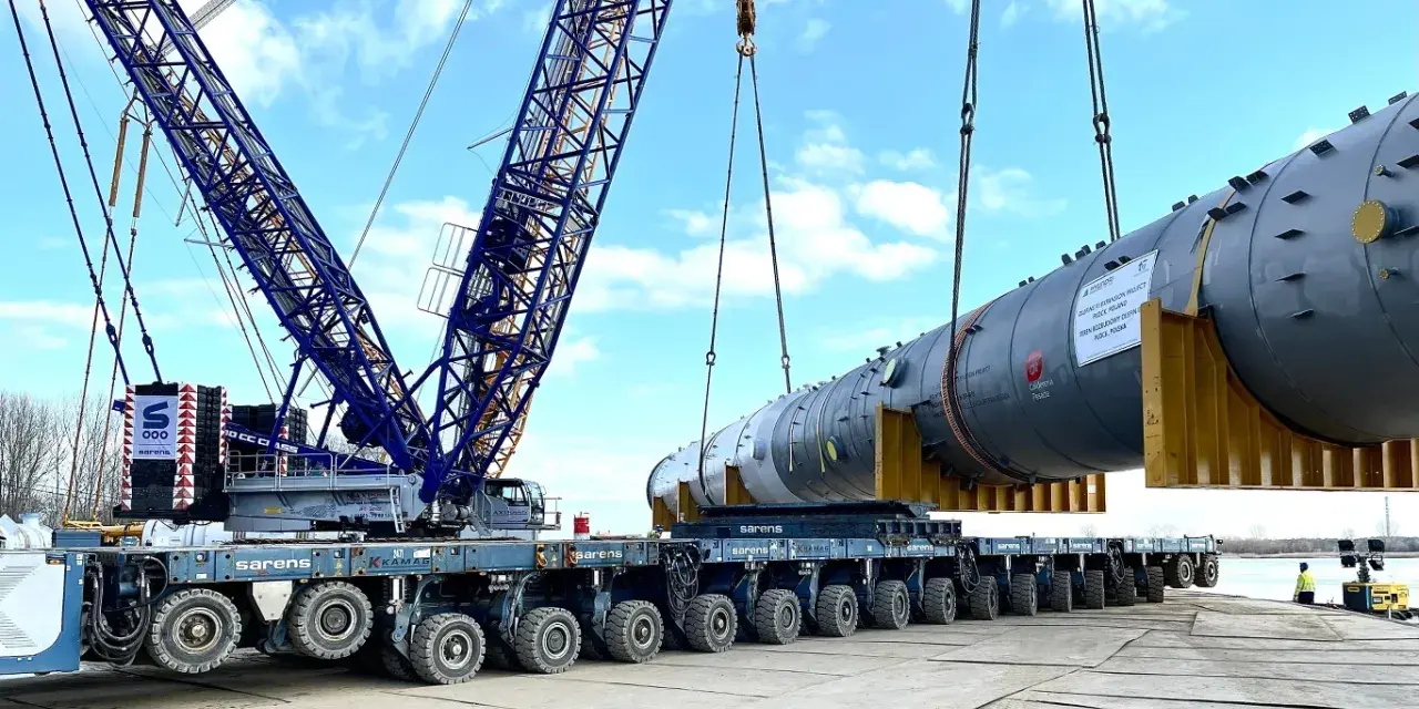 Największy transport w Polsce: potężny dźwig Sarens podnosi ogromny element instalacji na wielokołową platformę.