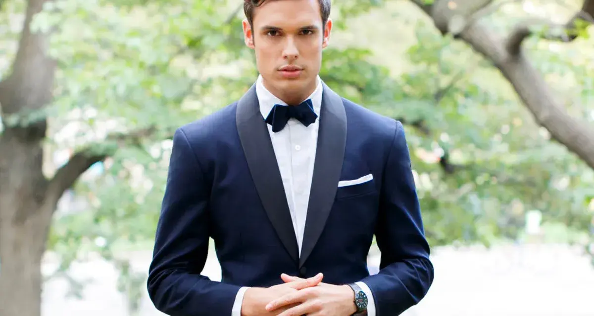 Uomo con smoking blu scuro, papillon e fazzoletto bianco. Il colore abito padre dello sposo è elegante e raffinato.