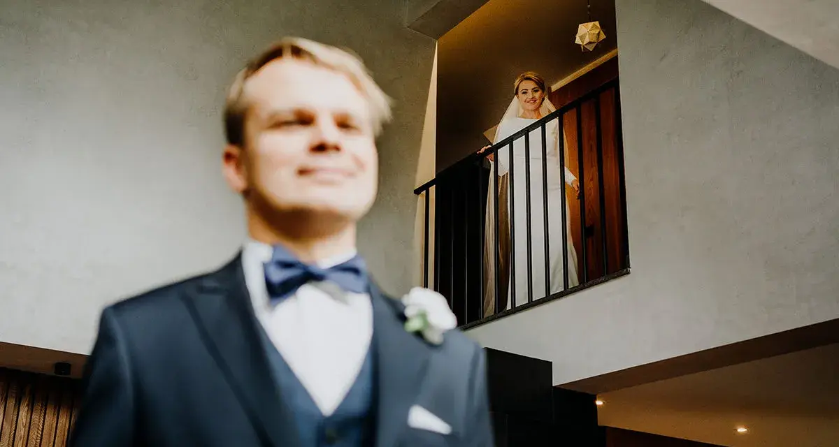 Pan młody w garniturze i panienka młoda w bieli na balkonie. Zastanawiasz się, ile bierze fotograf za wesele?