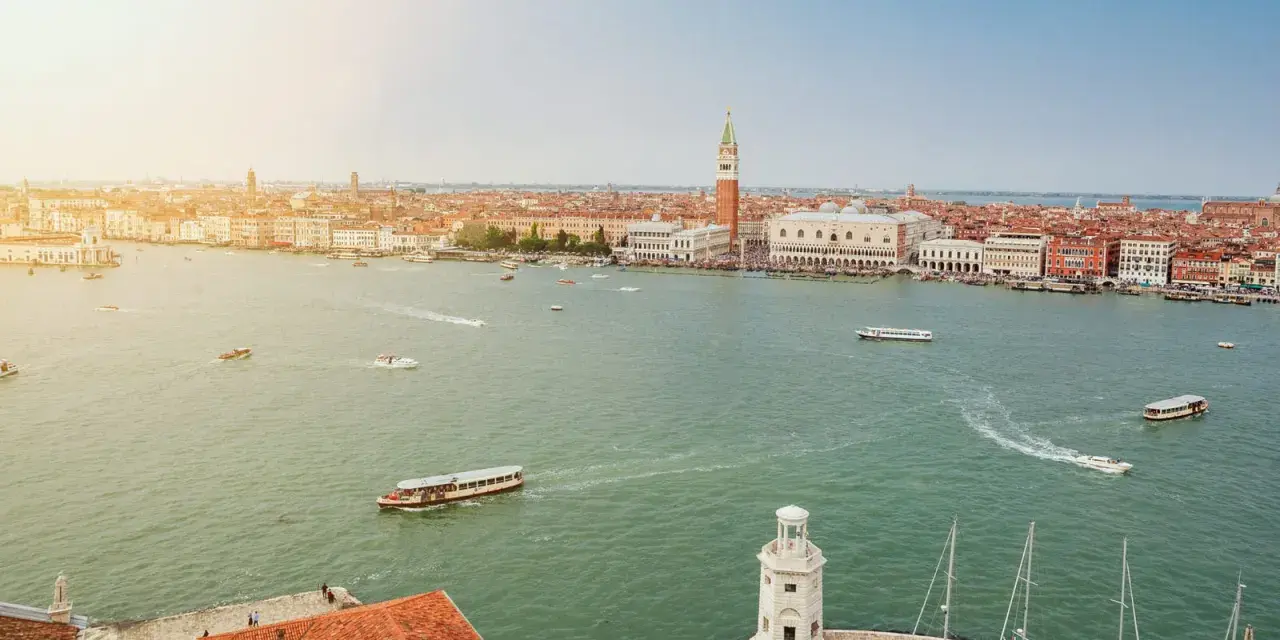 Vista aerea di Venezia con il Canal Grande, imbarcazioni e la famosa arte della città sullo sfondo.
