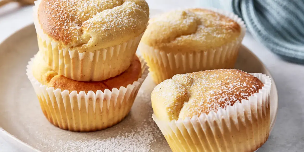 Saftige Quark Muffins, bestäubt mit Puderzucker, auf einem Teller.