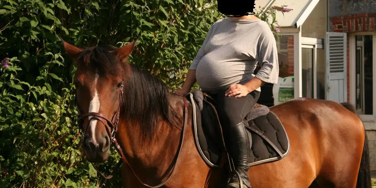 Une femme enceinte profite d'une balade à cheval, un moment de sérénité avant l'arrivée de bébé. L'équitation et grossesse, une combinaison harmonieuse.