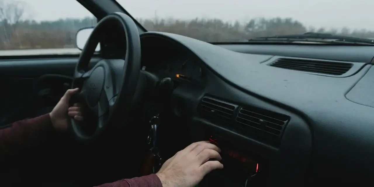 Dłoń kierowcy reguluje radio samochodowe.