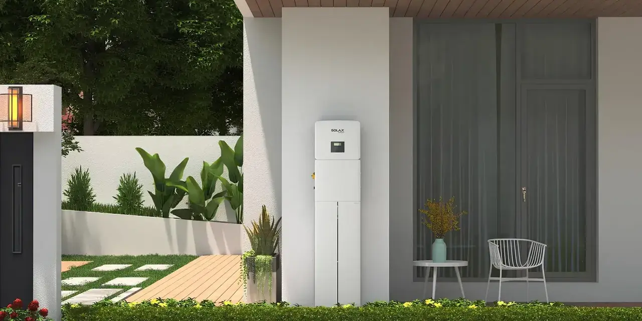 Biały magazyn energii 5 kW, stojący przy nowoczesnym domu, z zielenią i tarasem. Zastanawiasz się, na ile wystarczy taki magazyn energii?