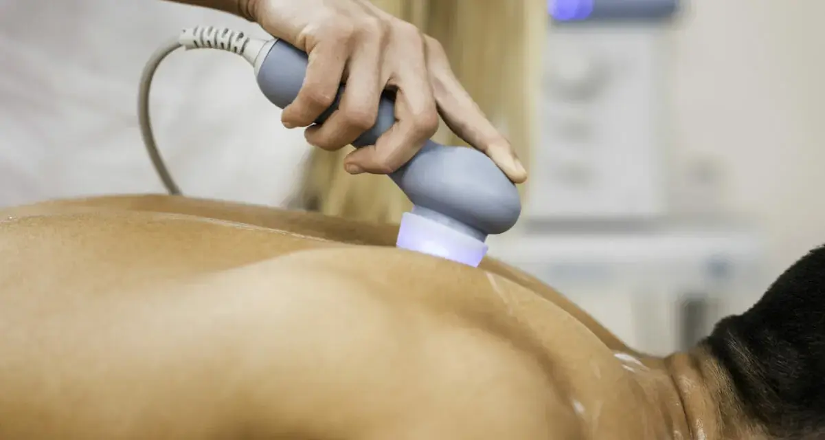 Physiotherapeutin behandelt Rückenschmerzen mit Ultraschall. Die Behandlung lindert Schmerzen nach Verletzungen.