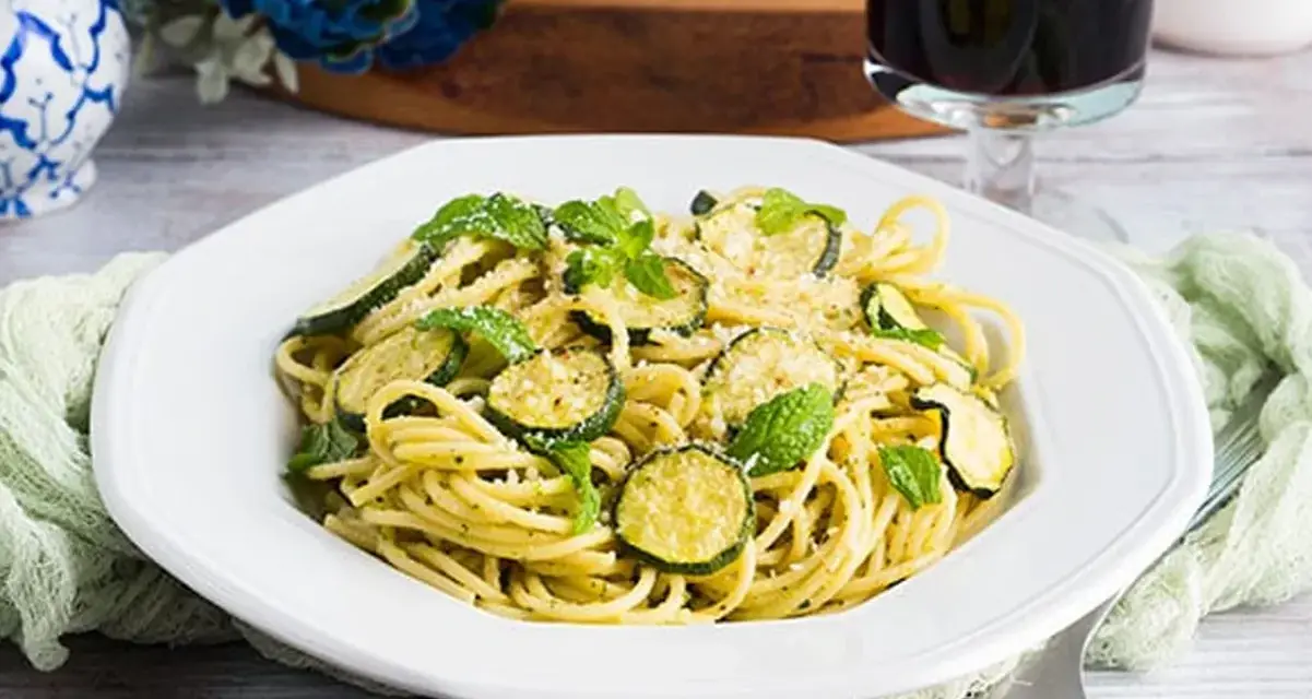 Un piatto di pasta e zucchine alla siciliana, guarnito con menta fresca e parmigiano.