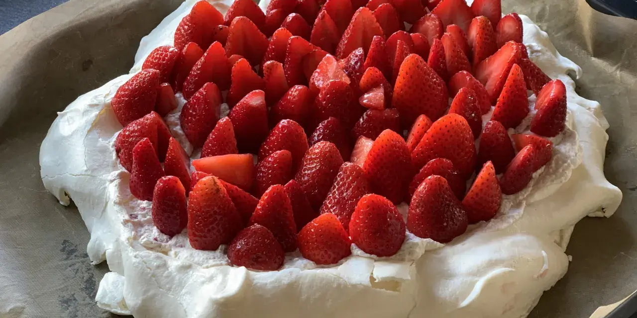 En stor pavlova i långpanna, täckt med vispgrädde och massor av färska jordgubbar. Perfekt för sommarens firanden!