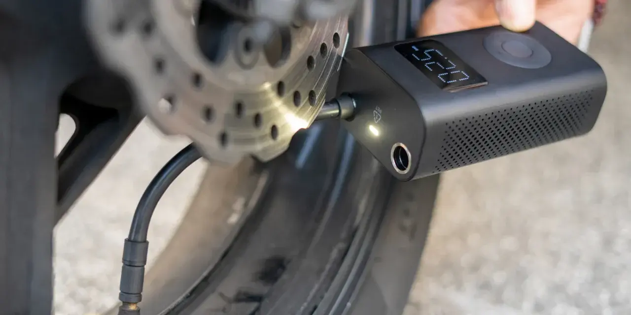 Gonfleur de pneu sans fil connecté à la valve d'une roue de moto, affichant la pression.