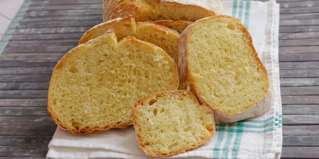 Fette di pane di semola dorato, con la crosta croccante e la mollica soffice, su un canovaccio a righe.