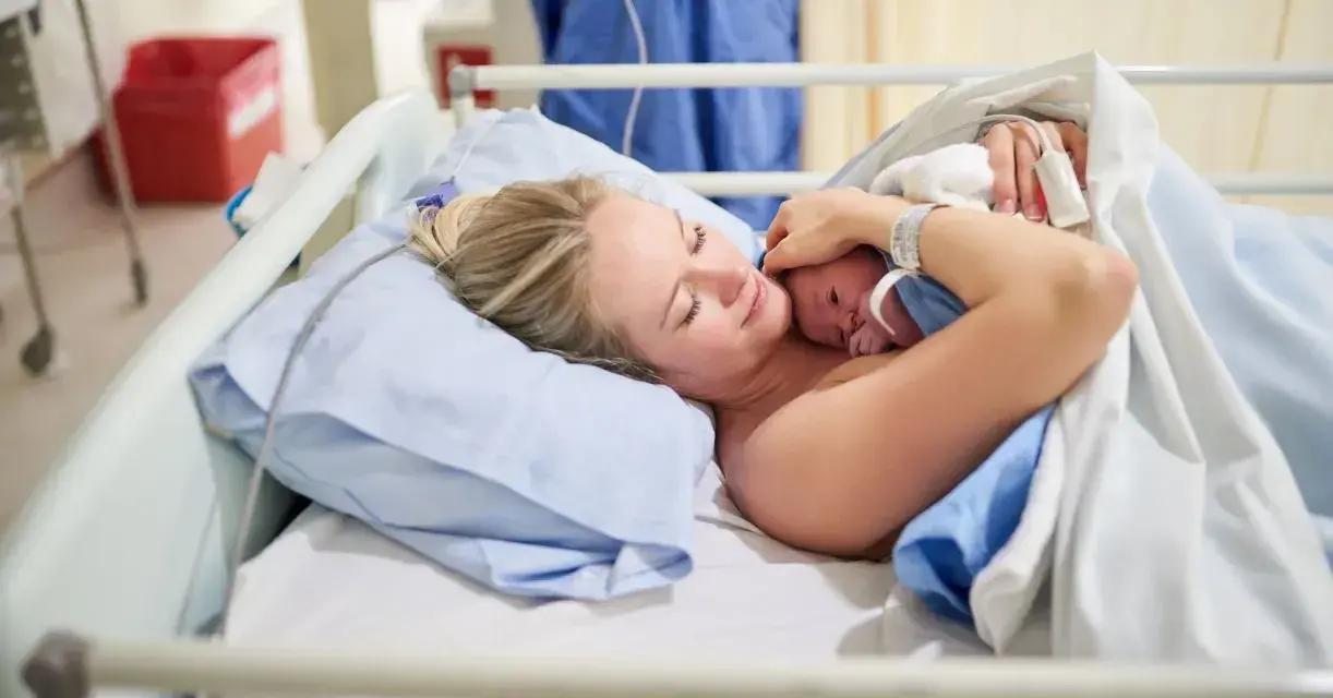 Szczęśliwa mama tuli noworodka. To początek jej urlop macierzyński, pełen miłości i czułości.