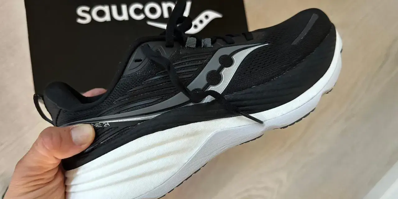En svart Saucony löparsko, modell Guide 24, hålls upp. Denna sko är designad för att ge stöd och stabilitet, vilket är viktigt för att förstå vad pronation betyder för löpare.
