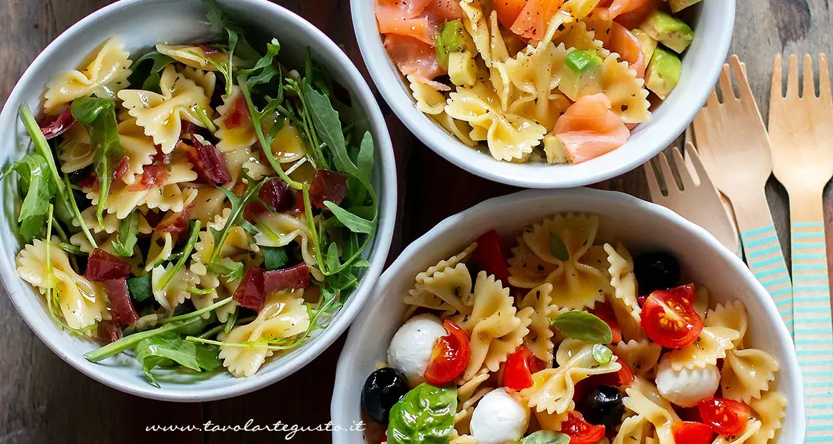 Tre ciotole di pasta fredda saporita: una con salmone e avocado, una con rucola e prosciutto, e una con pomodorini, mozzarelline e olive.