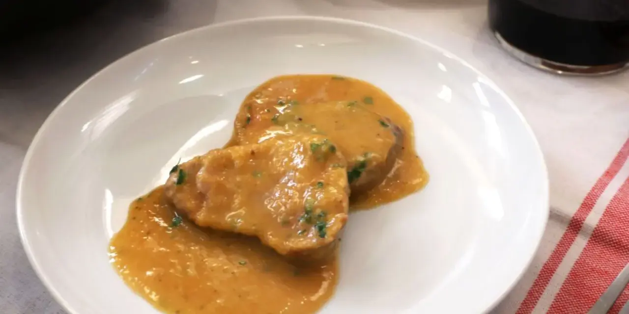 Dos medallones de solomillo al ajillo en una salsa cremosa, servidos en un plato blanco.