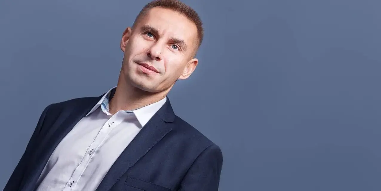 Mężczyzna w garniturze i białej koszuli, patrzący w górę.
