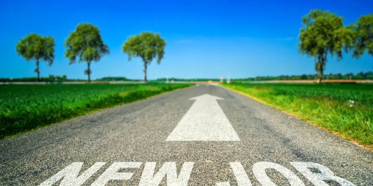 Strada asfaltata con freccia bianca e scritta "NEW JOB". Un percorso verso un futuro luminoso, ideale per chi sta pensando di cambiare lavoro a 30 anni.