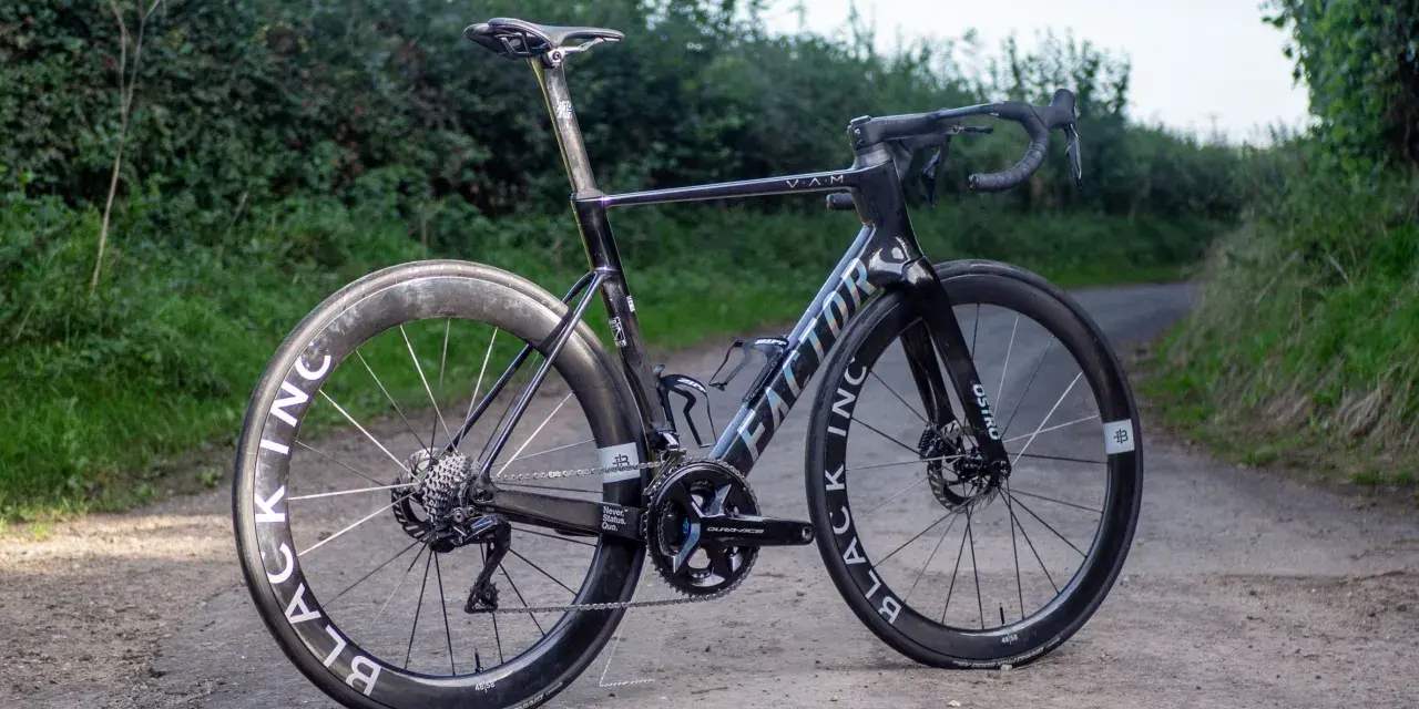 A black Factor Ostro VAM road bike with Black Inc wheels sits on a dirt path, ready for an adventure.