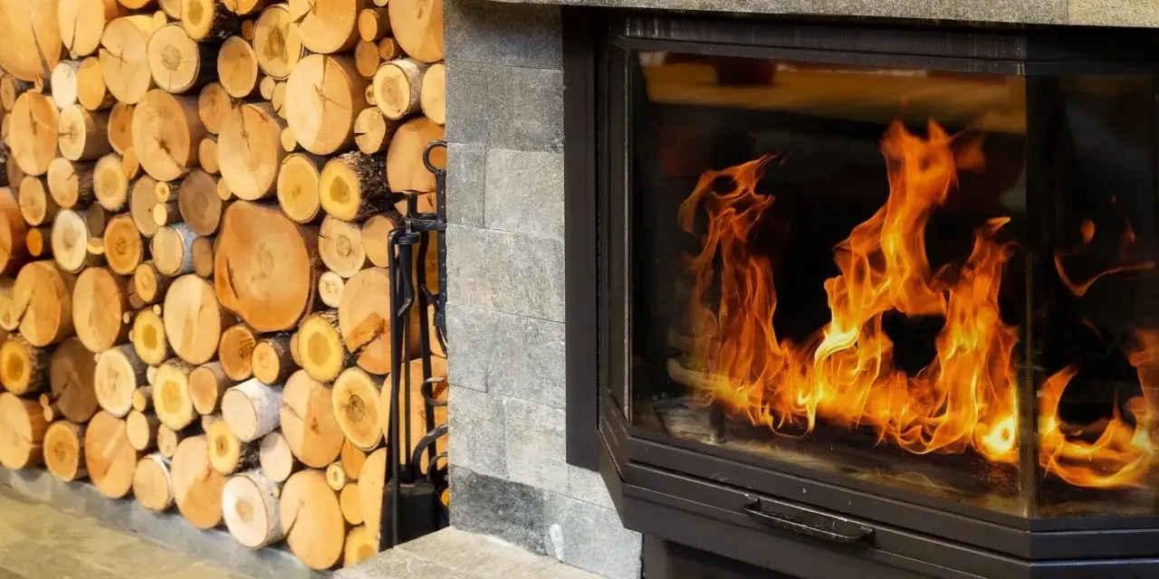 Leña apilada junto a una moderna insert chimenea con llamas danzantes.