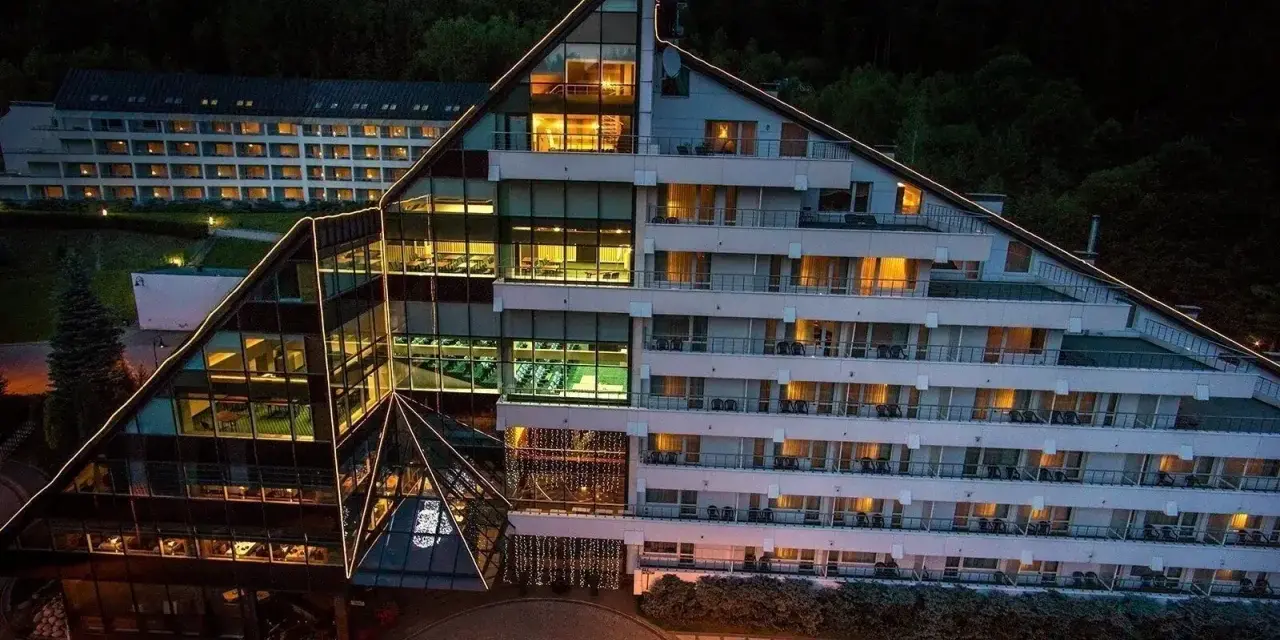 Nowoczesny hotel Klimczok Resort & Spa nocą, z oświetlonymi oknami i wejściem. Wiele pozytywnych hotel klimczok resort & spa opinie potwierdza jego urok.