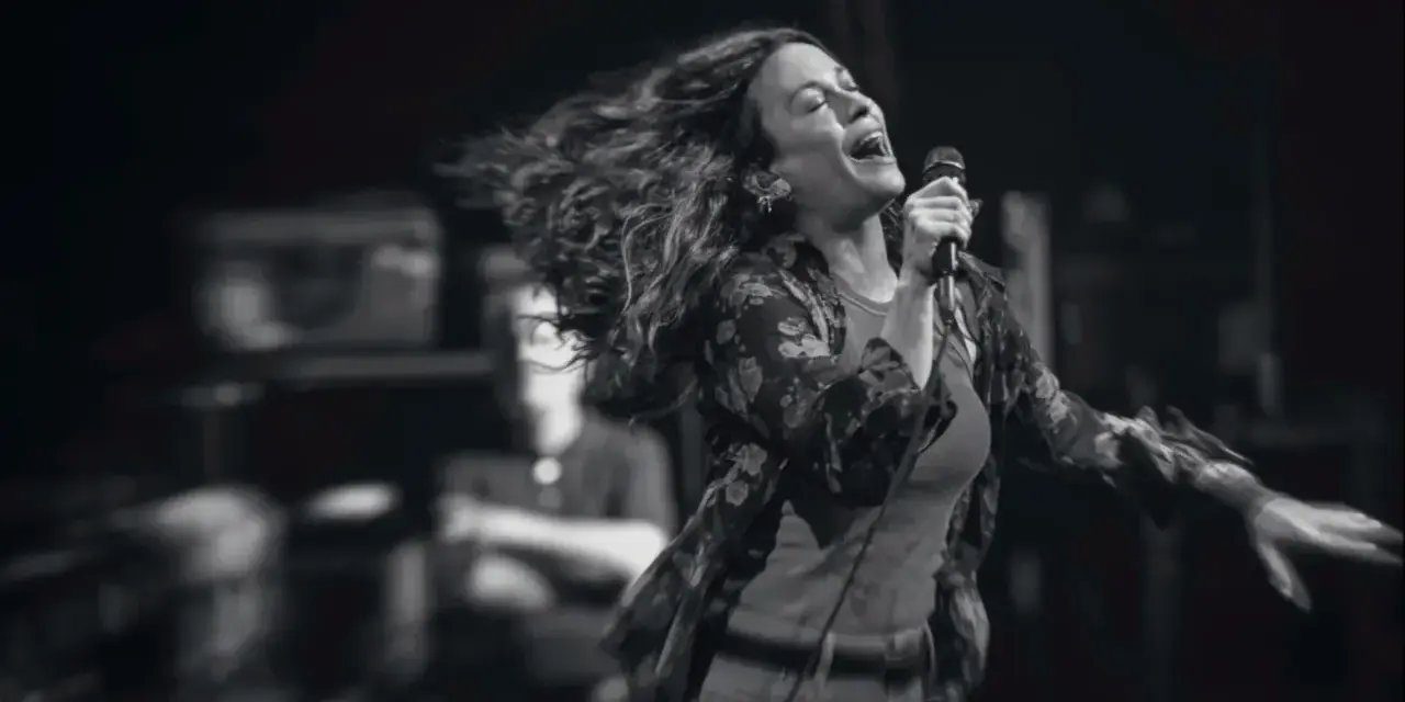 Energetyczny alanis morissette koncert, wokalistka śpiewa z pasją, włosy rozwiane w locie.