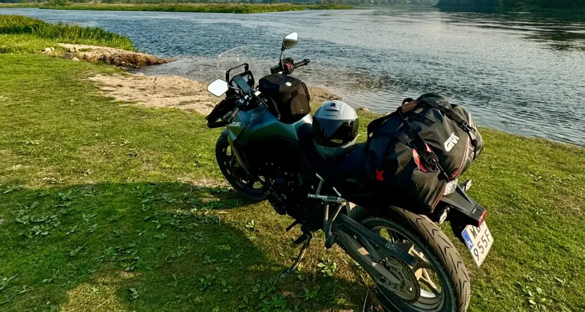 Motocykl z bagażem nad rzeką, gotowy do podróży po Litwie. Przepisy drogowe to podstawa bezpiecznej wyprawy.