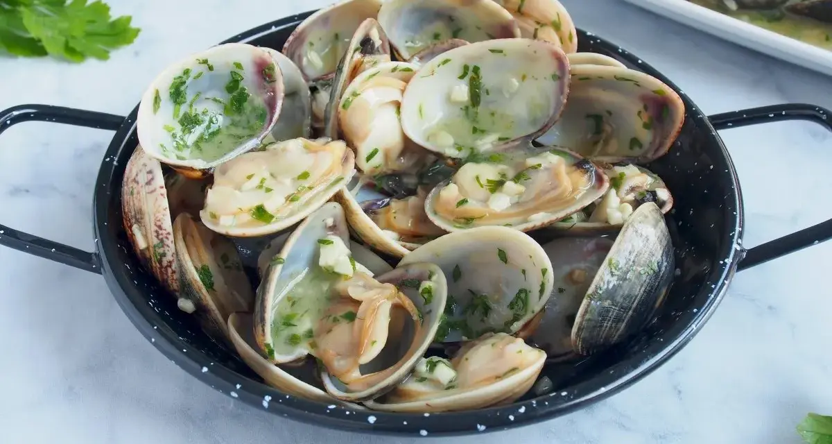 Almejas en salsa verde, un plato delicioso con mariscos frescos y perejil picado, listo para disfrutar.