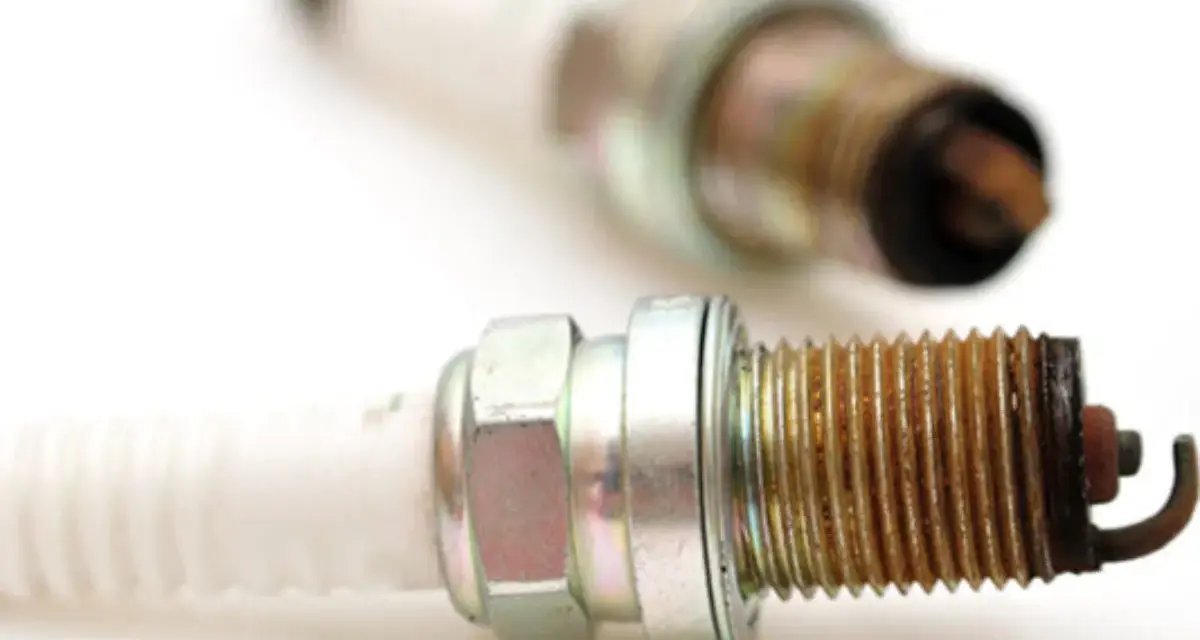Two used spark plugs for cars, showing wear and tear on their metal tips.