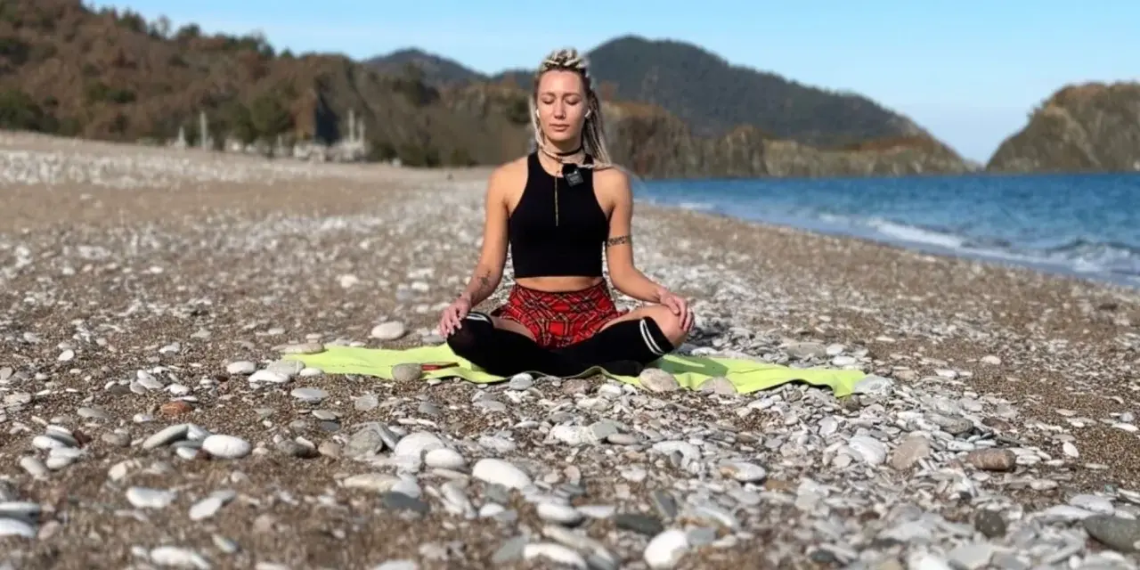 Frau in Meditation am Strand, tiefe Konzentration auf die Wellen.