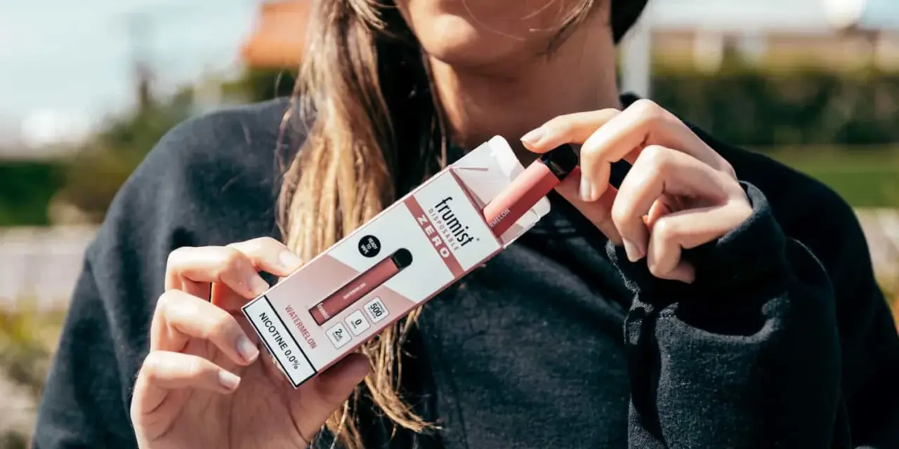 Mujer sosteniendo la caja de un vape desechable sabor sandía, sin nicotina.