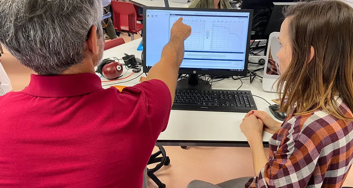 Un homme montre un audiogramme à une femme, lors d'une formation audioprothésiste Espagne à distance.