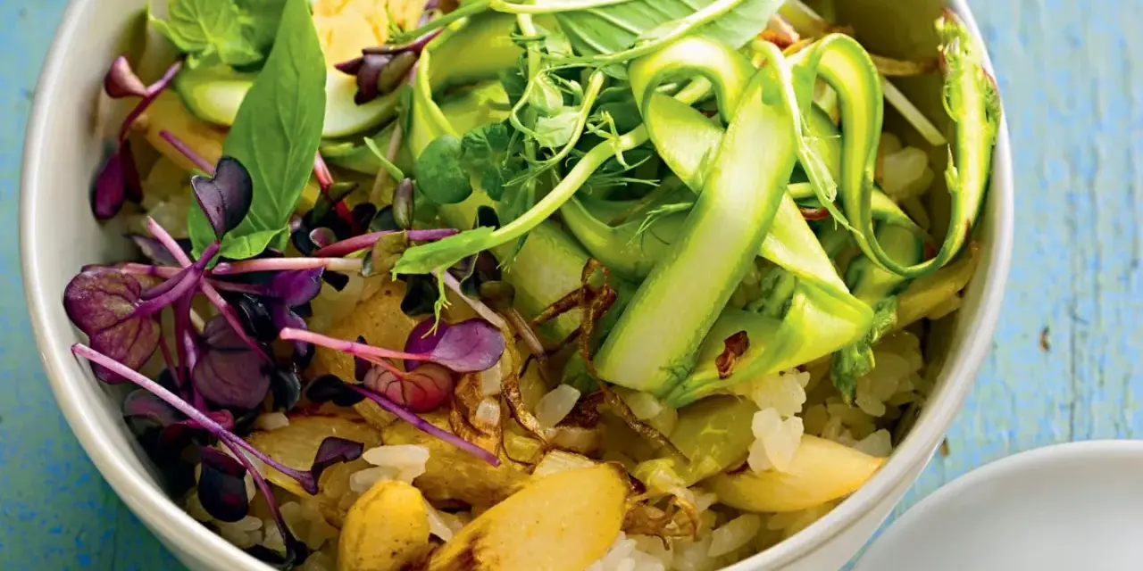 Eine bunte Spargel Bowl mit Reis, Ei, Sprossen und frischen Kräutern, appetitlich angerichtet.