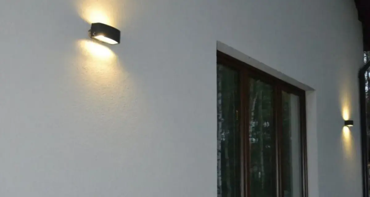 Nierówności na elewacji pod światło, podkreślone przez dwa kinkietowe punkty świetlne.
