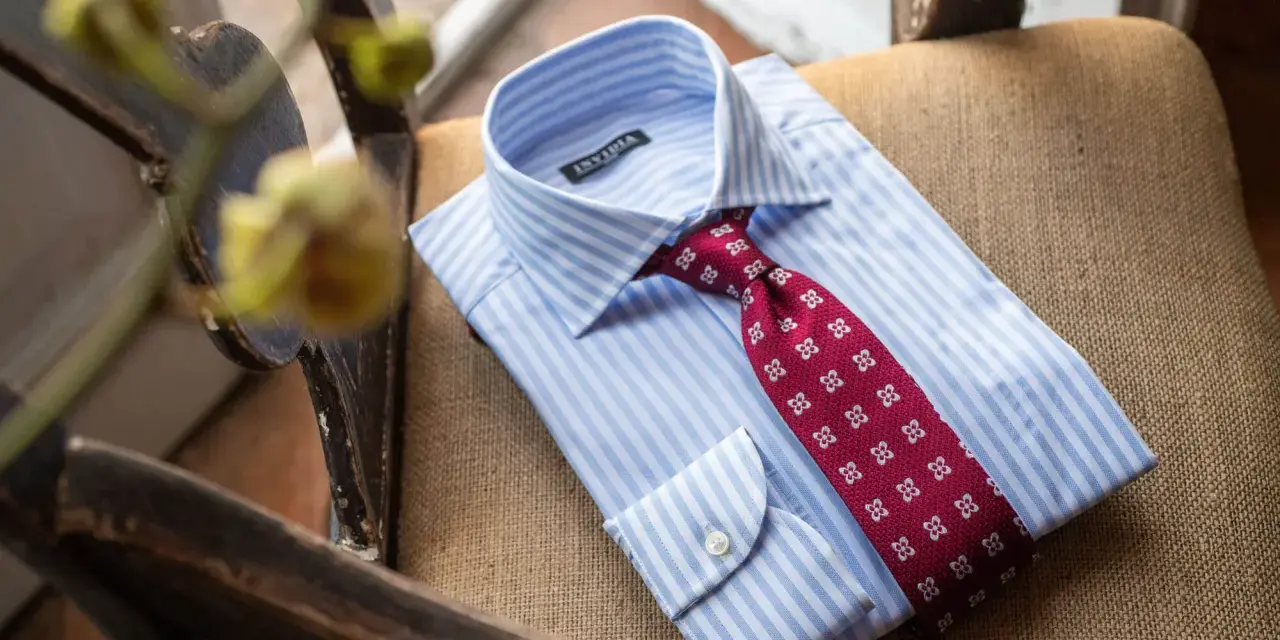 Camicia bianca a righe azzurre con cravatta bordeaux a fantasia floreale, pronta per un abito blu.