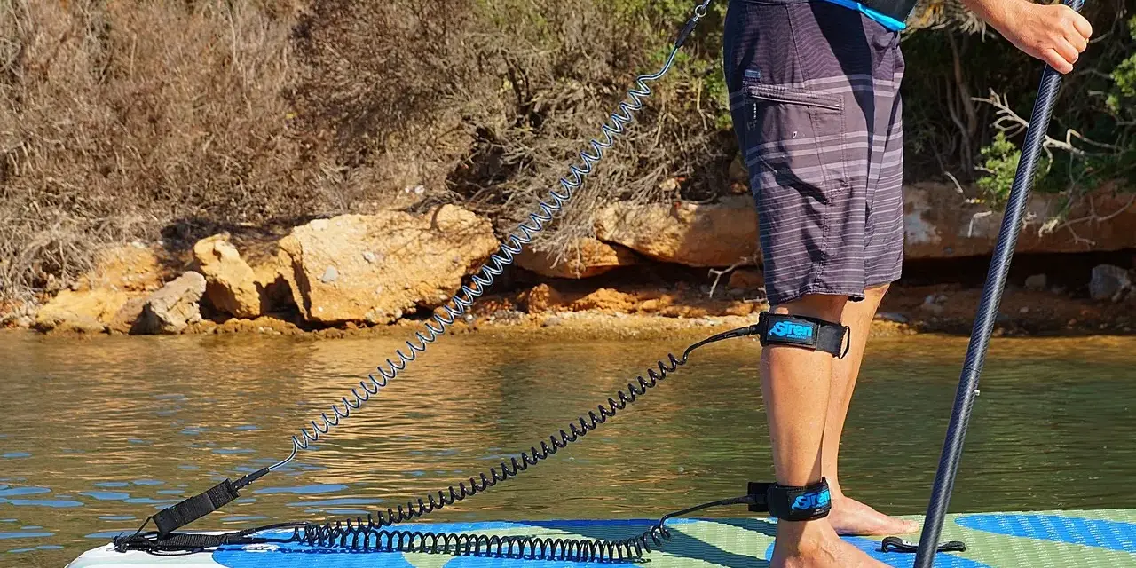 Person befestigt sup leash an Hüfte und Bein für sicheren Stand auf dem Board.