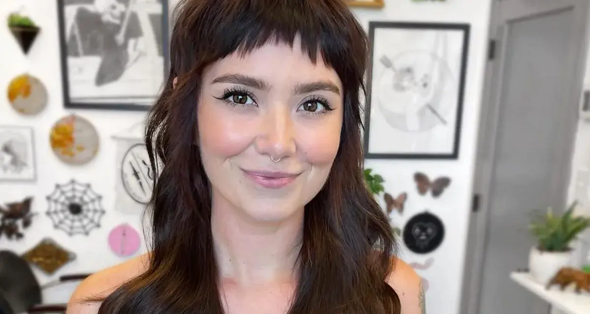 Uśmiechnięta kobieta z ciemnymi włosami i grzywką baby bangs.