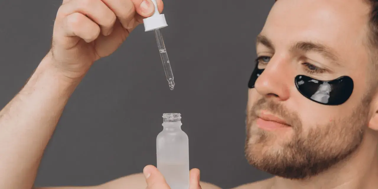 Homme avec patchs oculaires noirs appliquant un sérum. Découvrez les acide glycolique bienfaits pour une peau éclatante.