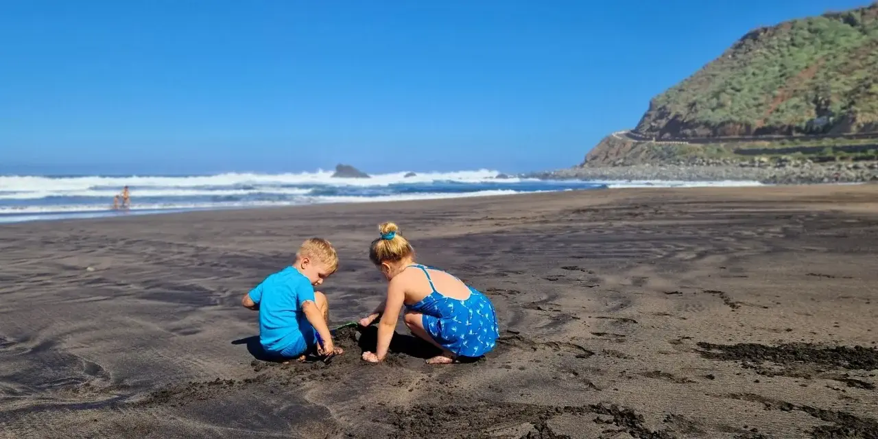 Dzieci budują zamki z piasku na czarnej plaży. Teneryfa atrakcje dla dzieci to raj dla małych odkrywców.