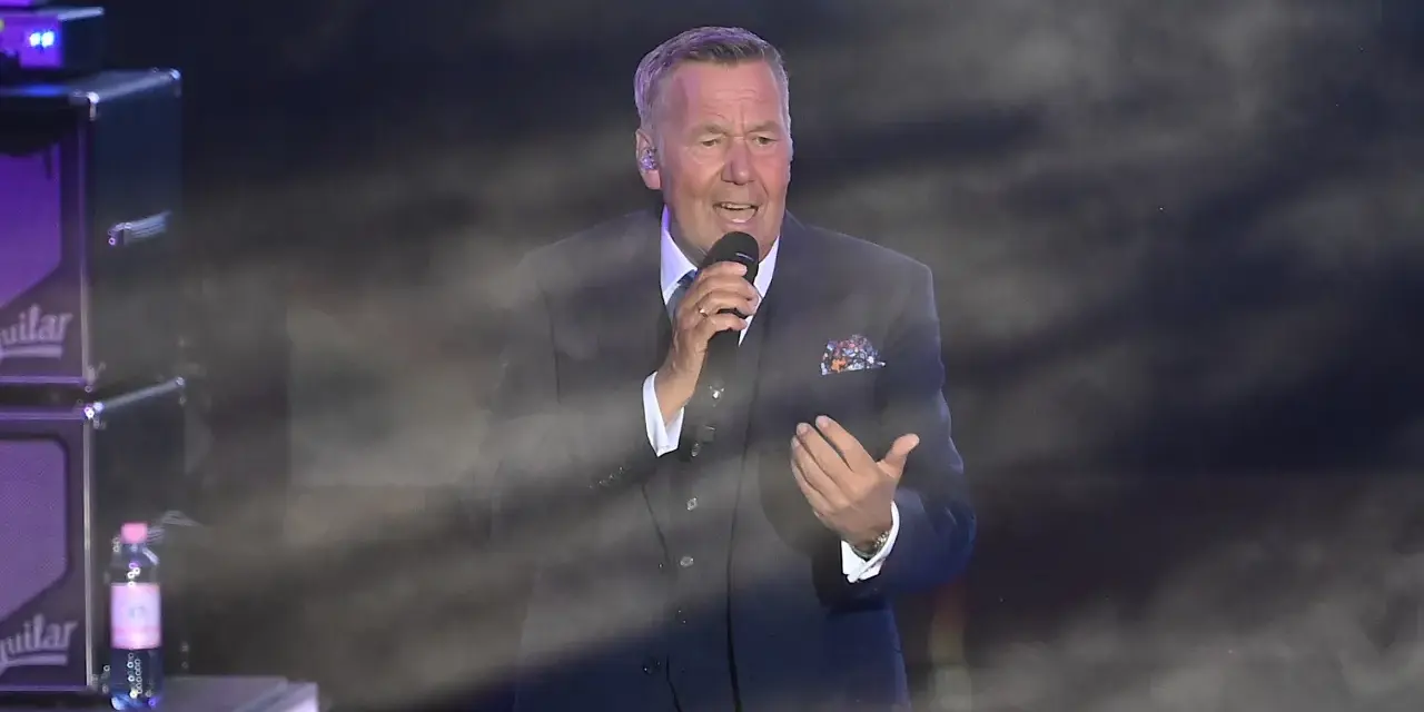 Roland Kaiser singt in Berlin. Der Künstler trägt einen dunklen Anzug und hält ein Mikrofon.