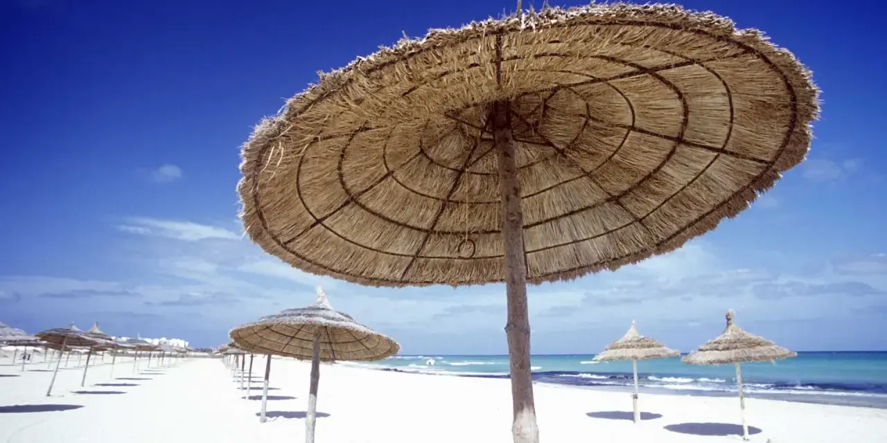 Słomiane parasole na pustej plaży. Piękna, słoneczna pogoda w Tunezji w listopadzie, idealna na spacer.